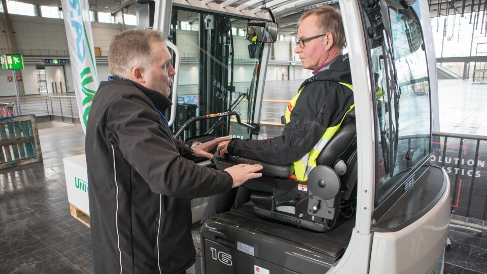 Produktsjef hos UniCarriers Mikael Pålsson forteller det svenske jurymedlemmet Mats Udikas om TX3s fortreffeligheter innen ergonomi. Truckens ratt er under Udikas venstre hånd.