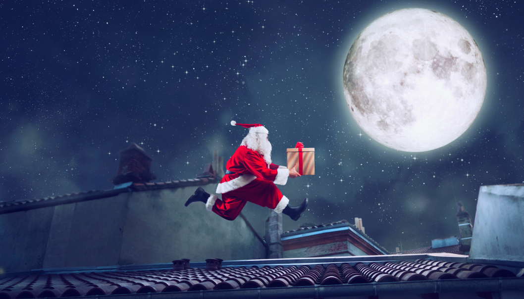Santa Claus runs on a roof with a present