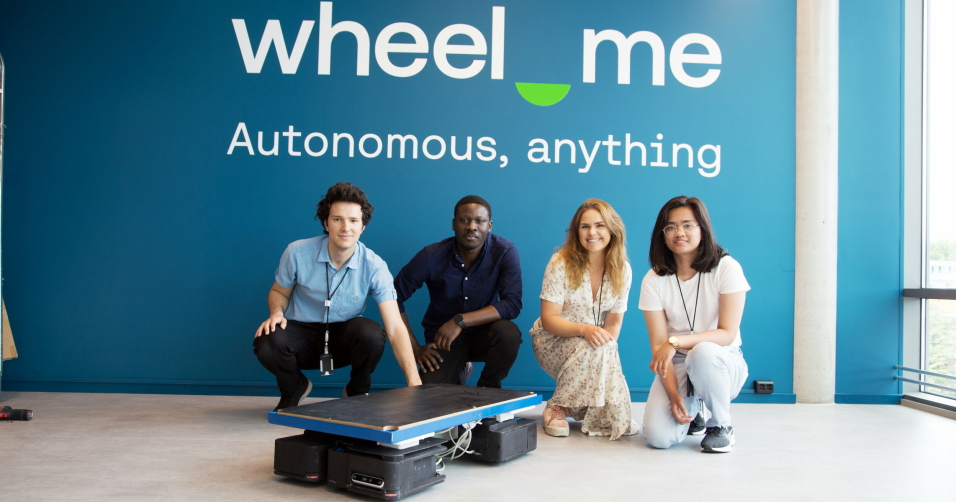 INTERNASJONALT MILJØ: Wheel.me har vokst raskt, og har over 50 ansatte fra totalt 29 ulike land. Fra venstre: Pol Ferrer Garcia, Ntiakoh Nicholas Kakra, Charlotte Heggem og Ceara Rojas. som alle er robotingeniører. Her foran en Wheel.me Frame som består av fire Wheel.me Genius-enheter, som det er mulig å montere hvilken lastbærer man ønsker oppå.
